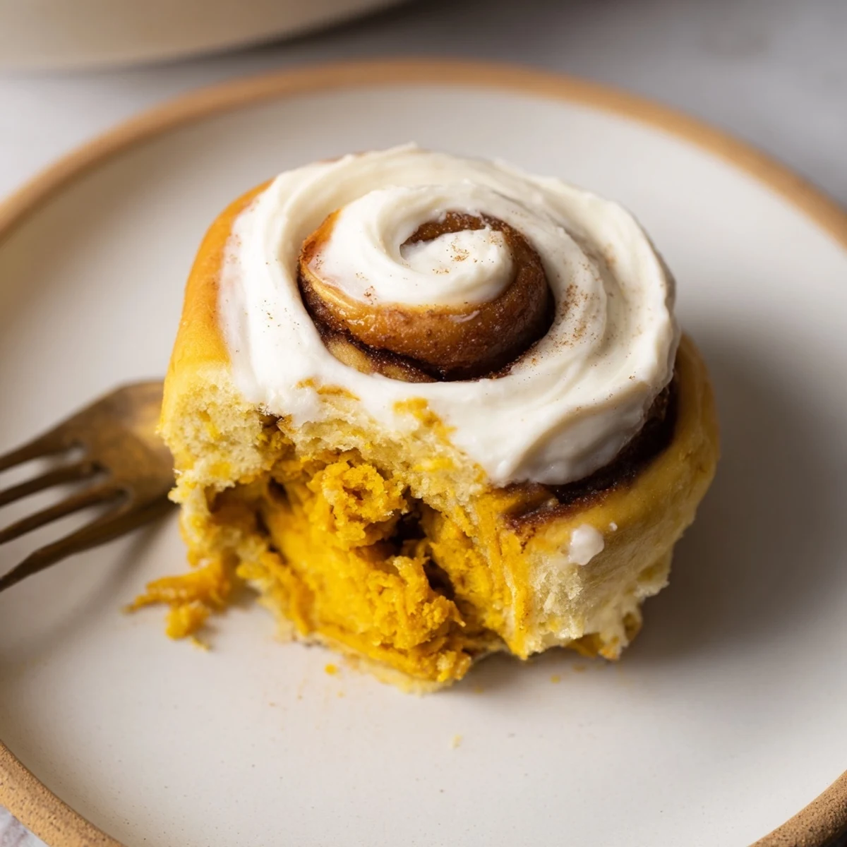 Fluffy pumpkin muffin stuffed cinnamon rolls drizzled with cream cheese frosting.