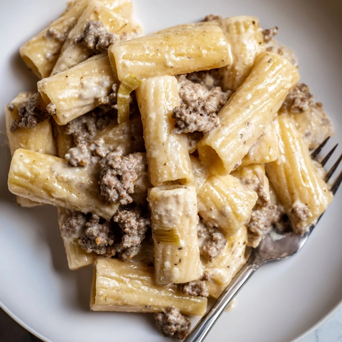 Savory creamy horseradish beef rigatoni garnished with fresh herbs on a plate.