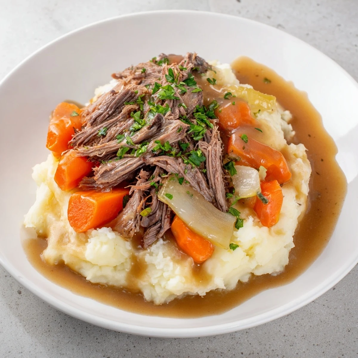 Fork-tender slow cooker pot roast, rich in gravy, served with fluffy mashed potatoes.