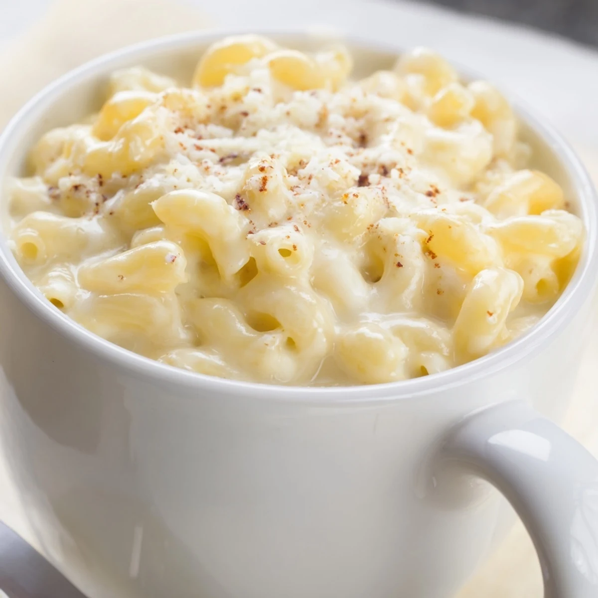Steaming hot mug mac & cheese with melted cheddar, ready for a comforting bite.