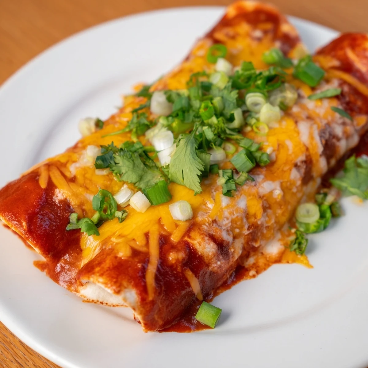 A close-up of cheesy, rolled Cheesy Bean Enchiladas, showcasing the hearty bean filling and delicious sauce.