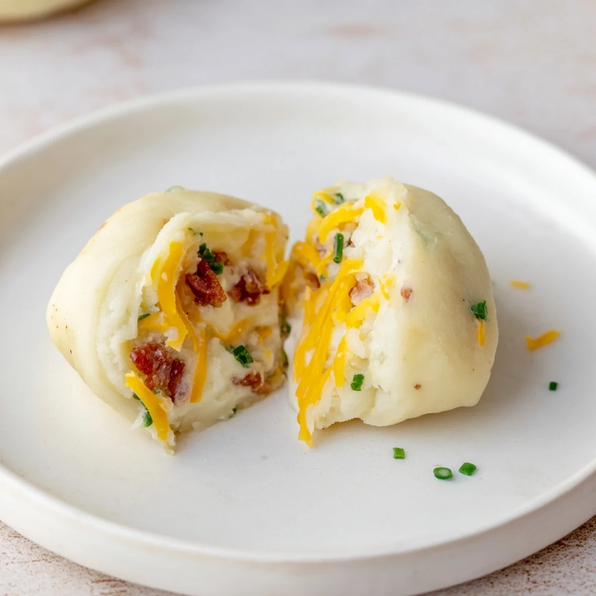 Close-up of freshly cooked Loaded Baked Potato Soup Dumplings, showcasing cheese, bacon, and chive garnish.