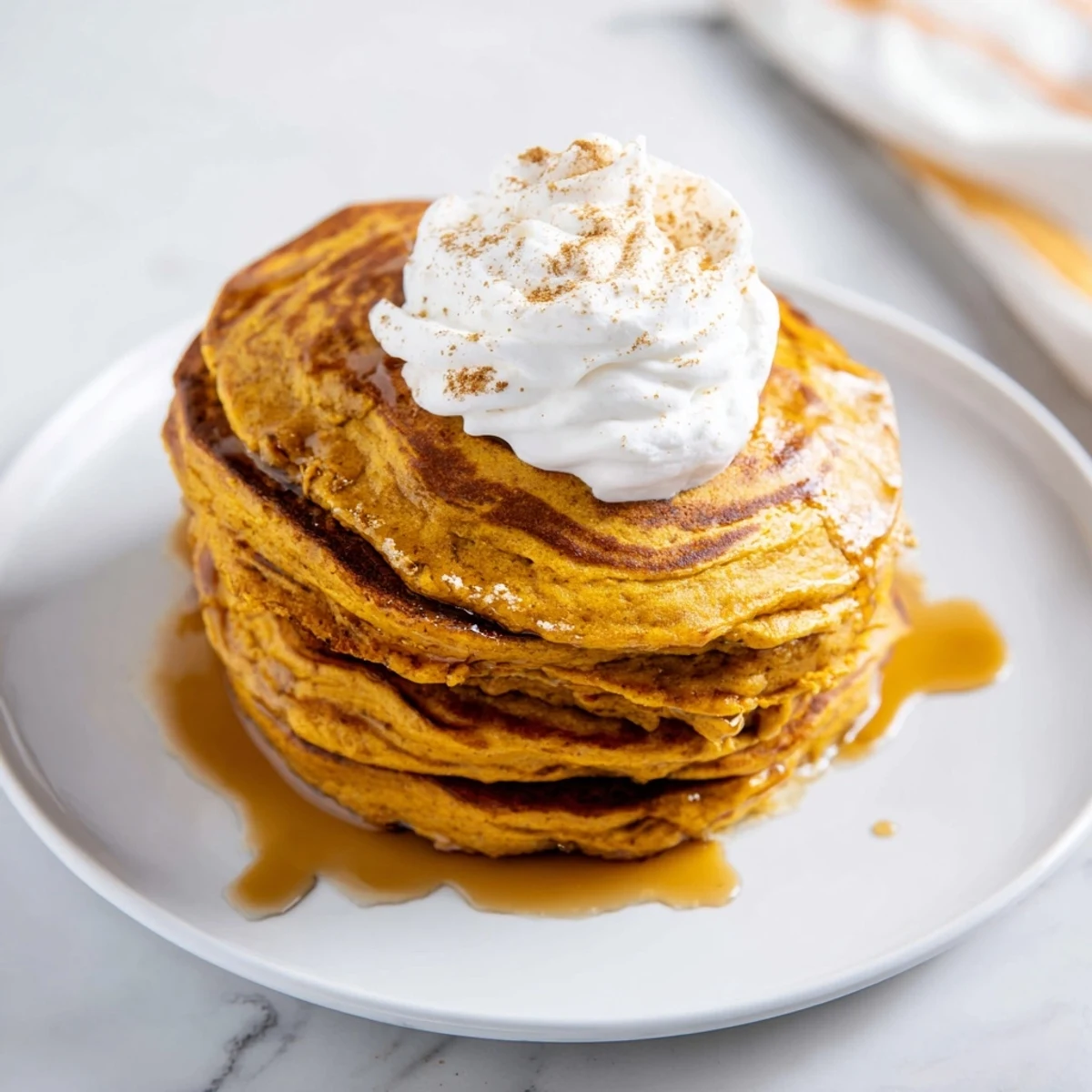 Golden-brown fluffy pumpkin spice pancakes stacked high, ready to be drizzled with sweet syrup.