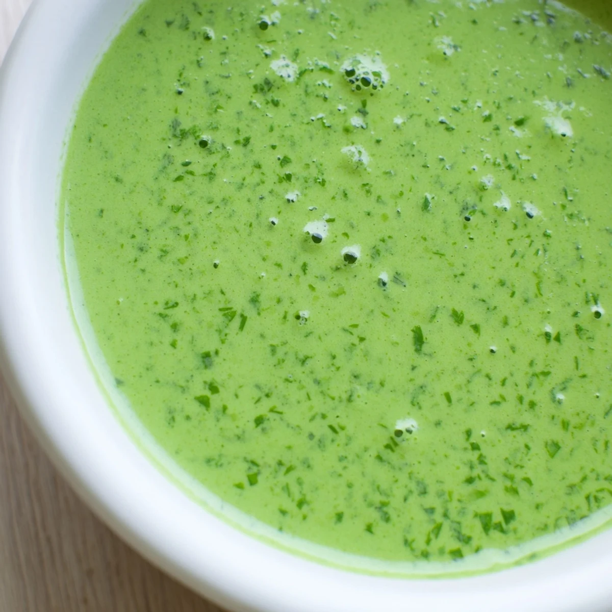 Bright green Green Goddess Dressing ready to drizzle over a fresh summer salad for a flavorful meal.