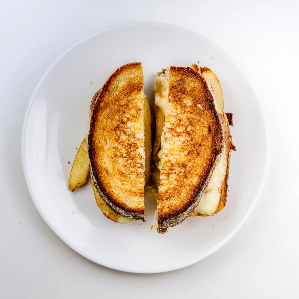 Golden-brown sourdough grilled cheese filled with melted smoked Gouda and thin, crisp apple slices, served warm on a rustic wooden board.