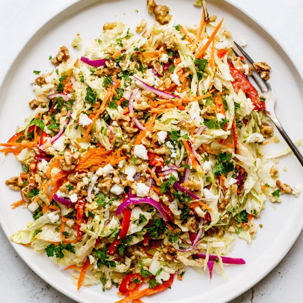 A bowl of warm Cooked and Loved Cabbage Salad with sautéed green cabbage, julienned carrots, and red bell pepper tossed in a tangy herb dressing.  