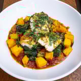 Vibrant image of Baked Cod with butternut squash, served with fresh parsley and a bright tomato-herb sauce.