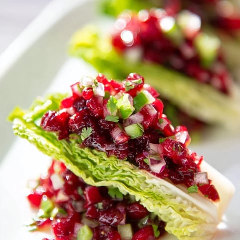 Vibrant cranberry jalapeño salsa boats nestled in crisp endive leaves for festive gatherings.  