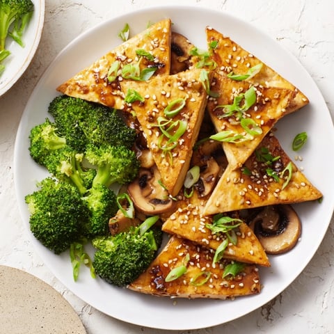 Golden, crispy Sautéed Tofu Steaks with vibrant broccoli, mushrooms, and savory sauce.