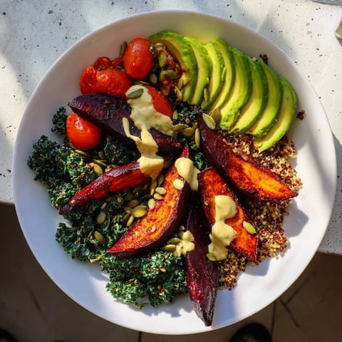 Vibrant quinoa, kale, and roasted beet bowl, drizzled with creamy tahini dressing, a healthy, flavorful lunch.