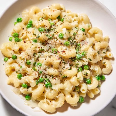 Steaming bowl of Macaroni & Peas, creamy and cheesy, ready for a satisfying dinner.