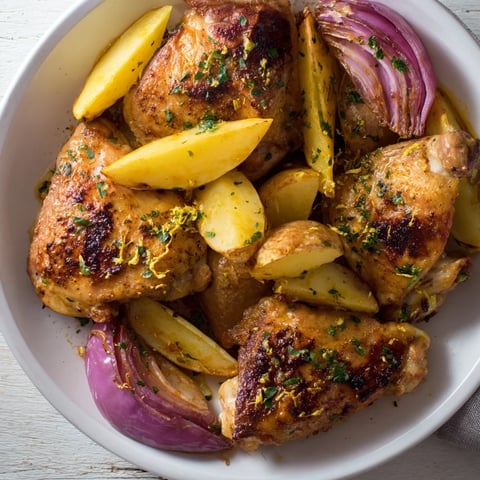 Golden Greek Lemon Chicken and Potatoes glistening with a vibrant lemon herb marinade, ready to serve.