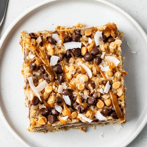 Golden-brown 7-Layer Magic Bars drizzled with sea salt caramel; a sweet, layered dessert.