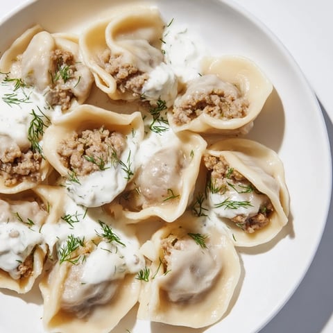 Steaming, golden Russian Pelmeni, freshly cooked and ready to be topped with sour cream.