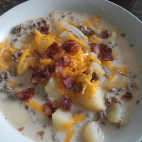 Close-up of a creamy Crockpot Cheeseburger Soup, showcasing tender potatoes and melting cheese over the beef.