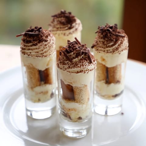 Bite-sized Countdown Tiramisu Shots with coffee-soaked ladyfingers and whipped cream, ready to serve.