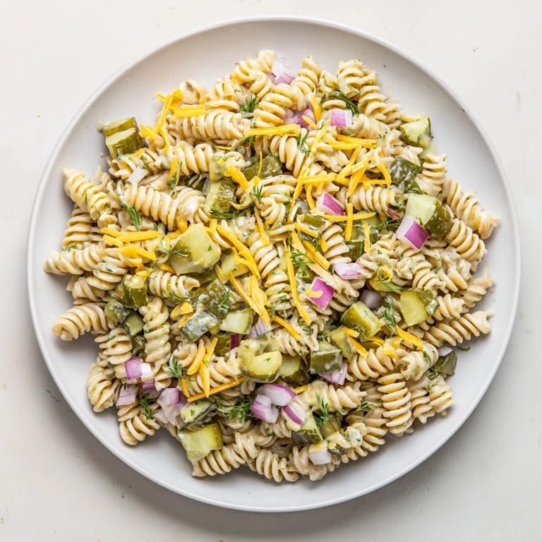 A vibrant bowl of Dill Pickle Pasta Salad with crunchy pickles, ideal for a summer picnic.