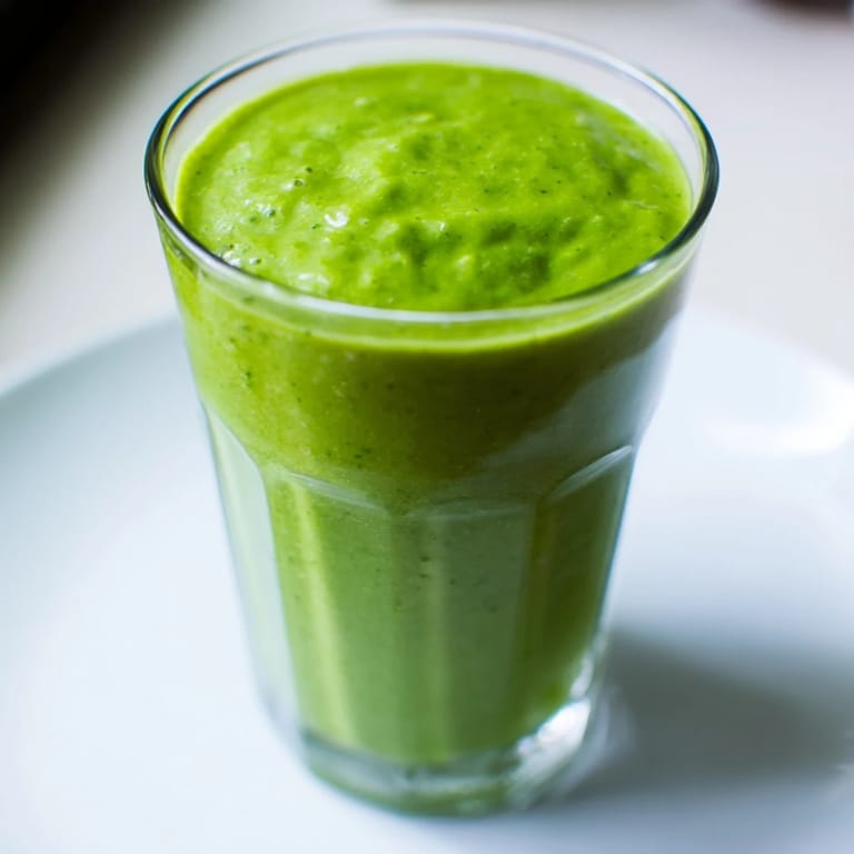 A glass overflowing with a Spinach Hidden Smoothie; a taste of tropical, fresh, and healthy flavors.