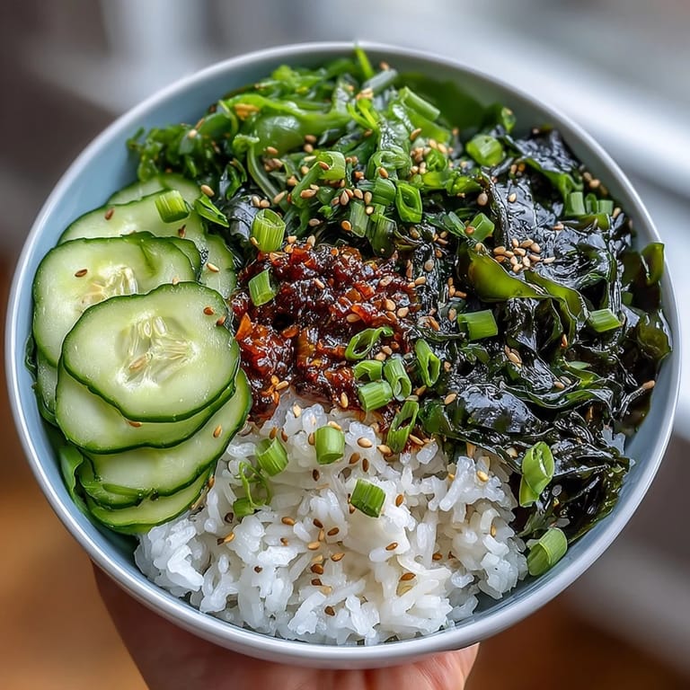 Colorful seaweed and nori rice bowl featuring tender sushi rice, rehydrated wakame, nori strips, and fresh cucumber slices in a vegetarian dish.