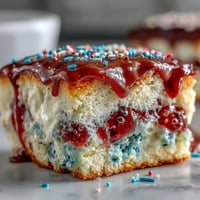 Festive Patriotic Poke Cake with creamy white chocolate ganache and red, white, blue swirls.