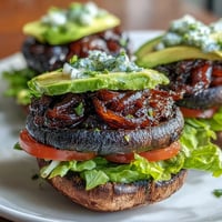 Juicy grilled portobello mushroom burgers piled high with creamy avocado, ready to serve.
