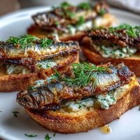 Golden crispy toasts with savory sardines and zesty lemon herb butter topping.